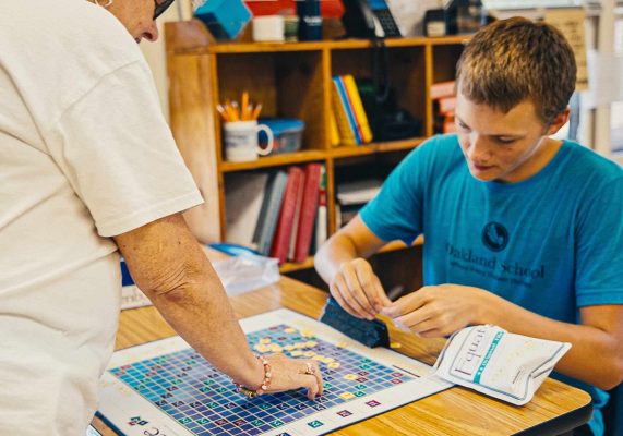 a teacher and student at Oakland School playing an educational game