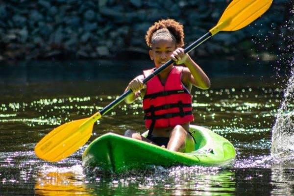 young camper kayacking on lake at camp friendship near Charlottesville