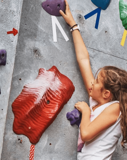 Girl reaching for handhold on rock wall