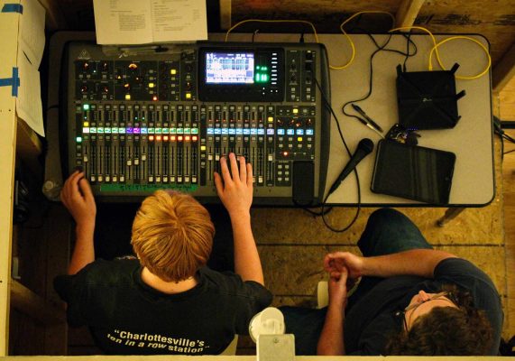 Photo of two people working at a radio station and using a sound mixer