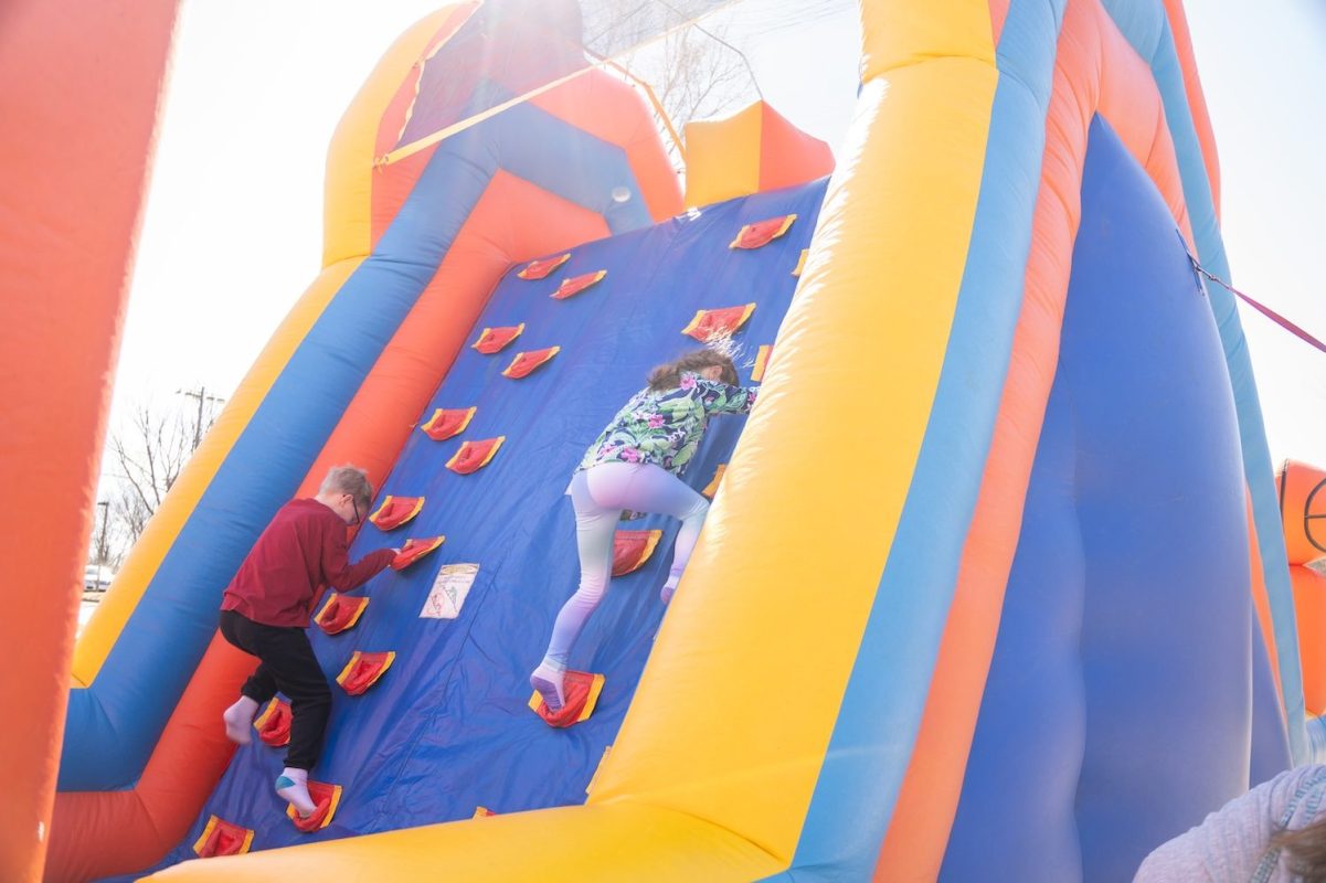 two kids climb up an inflatable bounce course at CharlottesvilleFamily Camp Expo and KidFest