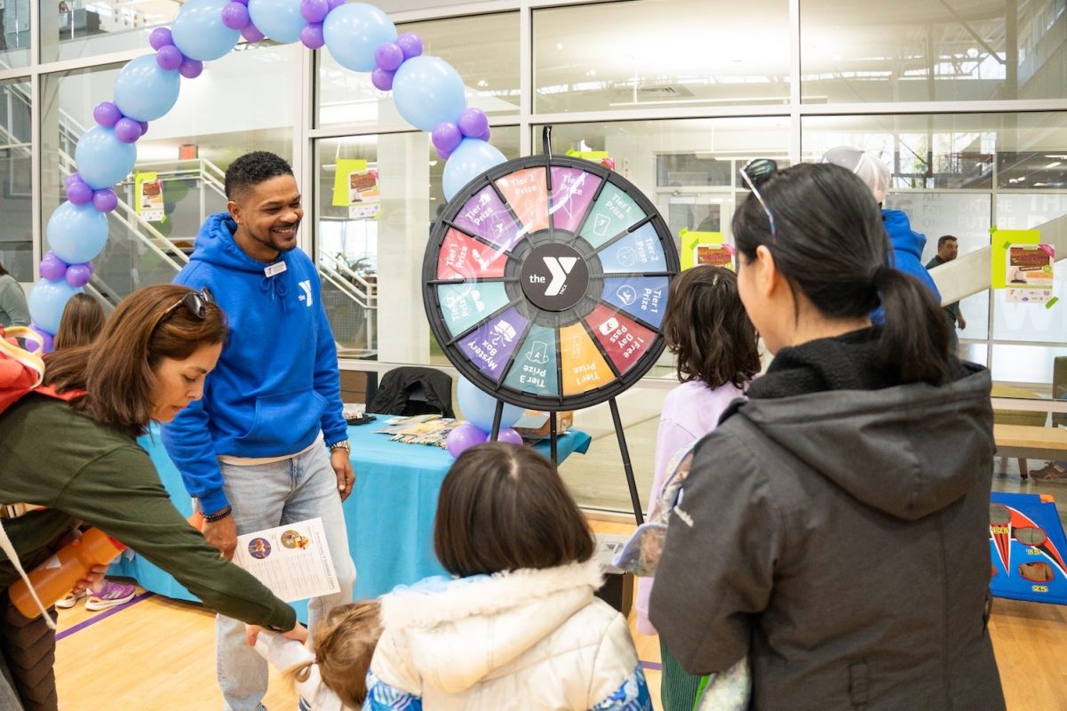 families spin price wheel with balloon arch in background at CharlottesvilleFamily Camp Expo and KidFest